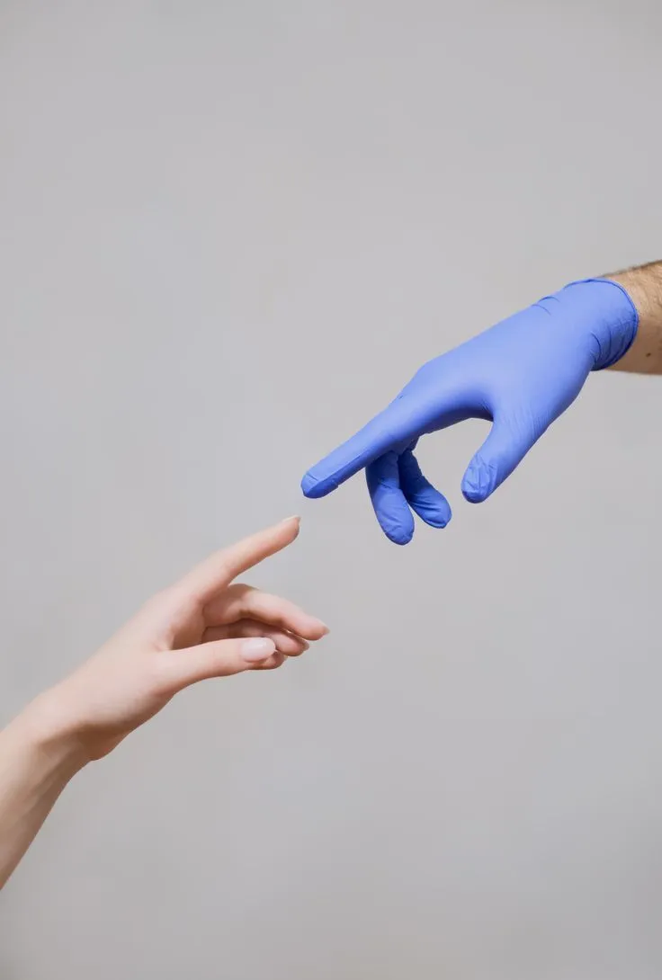 Una mano con guanto da odontoiatra si avvicina alla mano di una paziente